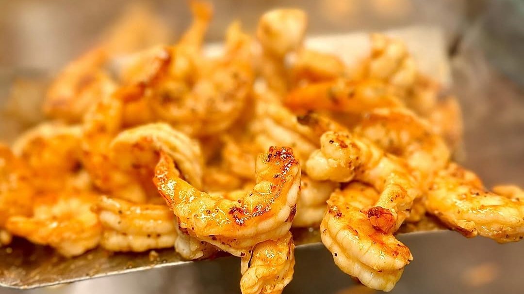 Hibachi shrimp lifted off the flat-top grill on a spatula at Bamboo Hibachi